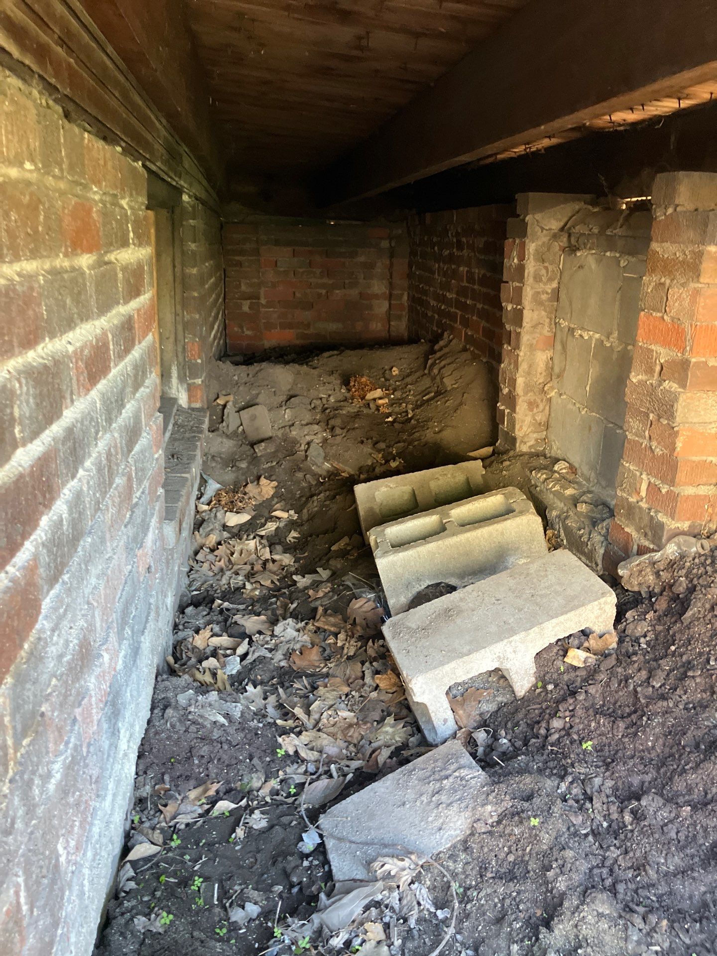 Epp Foundation Repair inspecting a dirty crawl space filled with debris and concrete blocks, highlighting the need for crawl 